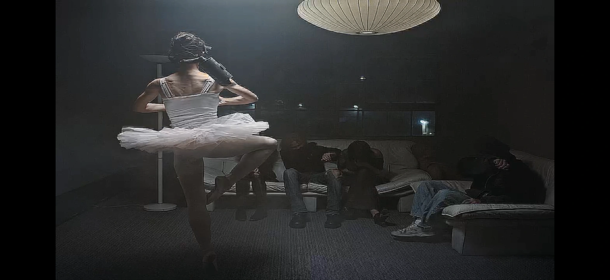 A masked ballet dancer in a living room beneath a paper lantern
