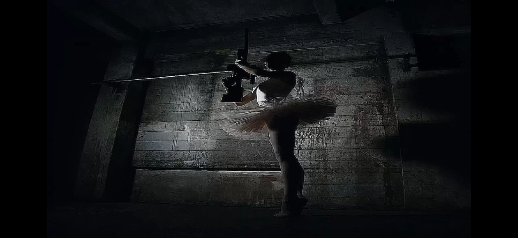 A ballet dancer seen from above against a dark floor