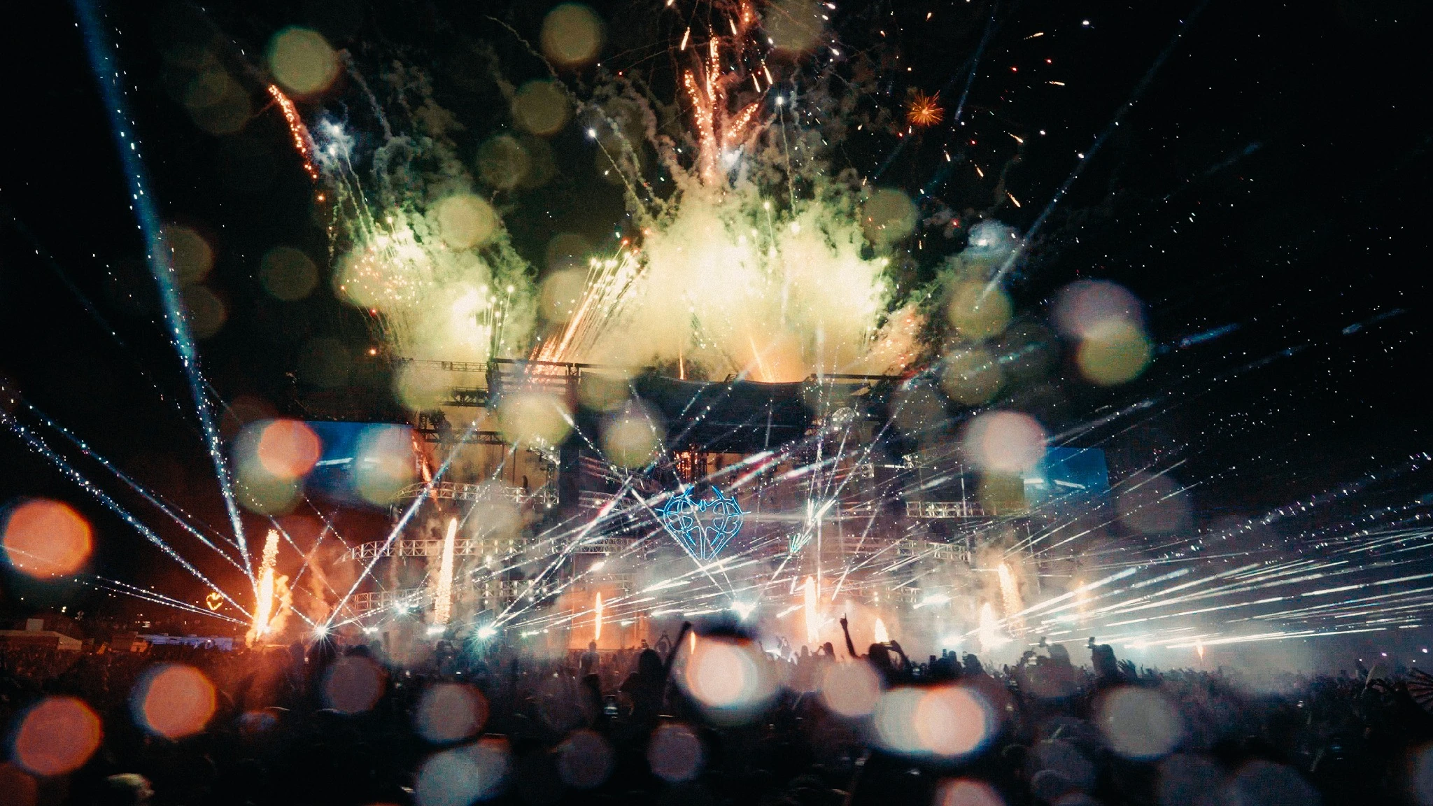 Fireworks and lasers over the Niteharts stage, seen through rain