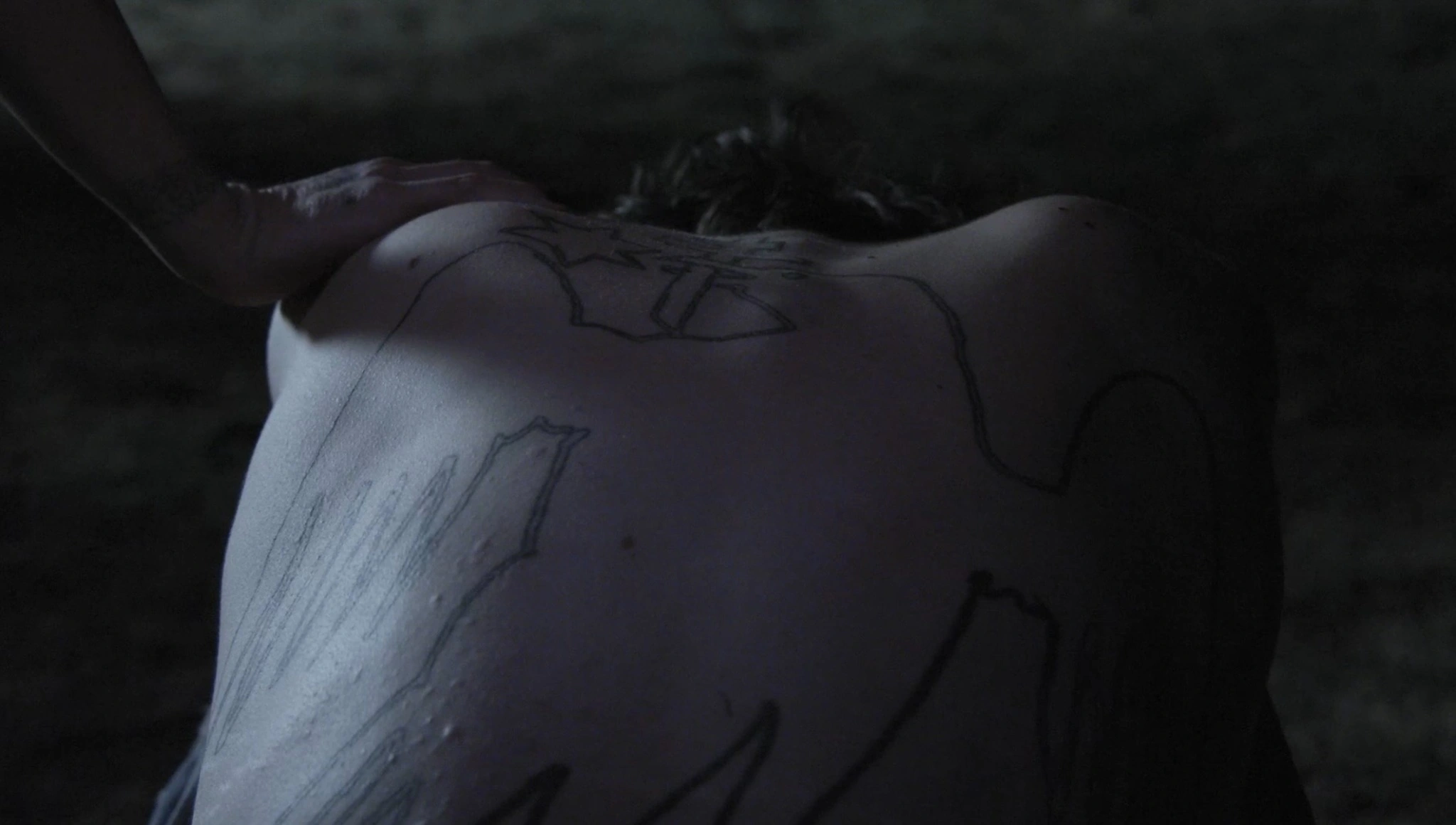 A hand resting on a tattooed back in MEANT TO BE