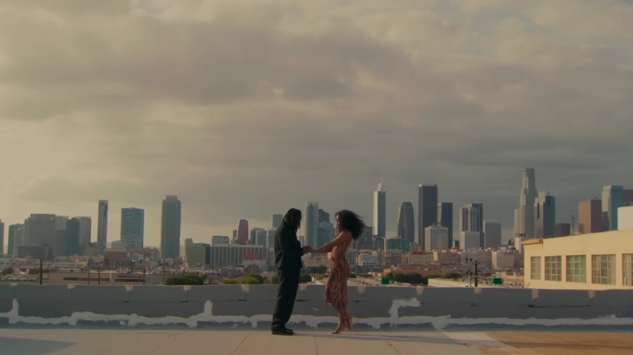 SiR and a woman holding hands on a rooftop overlooking the Los Angeles skyline