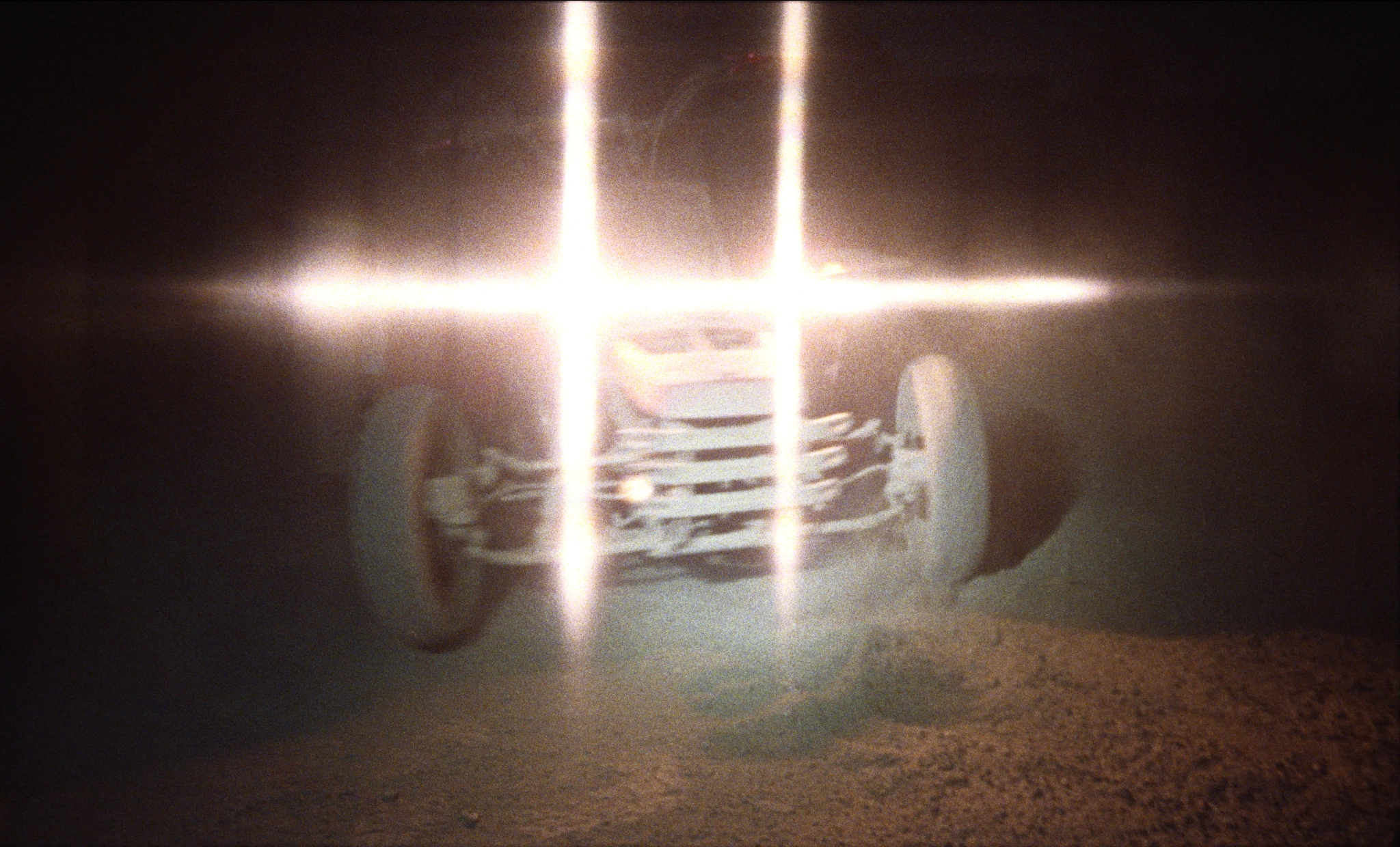 An off-road vehicle with headlights flaring across the frame